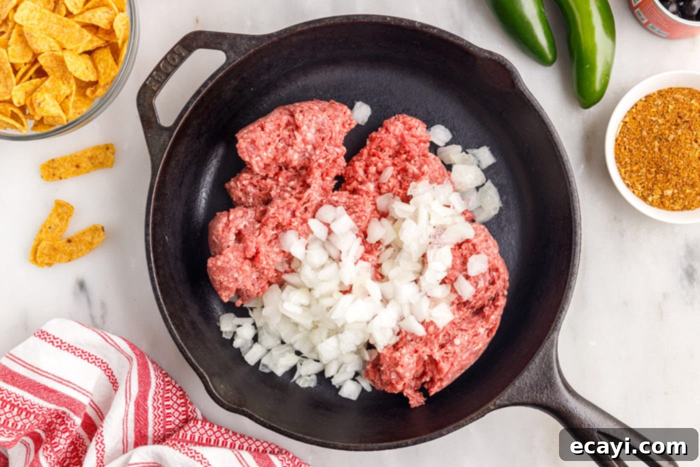 Crunchy Chili Cheese Delight 5 Ground beef and diced onion cooking in a large skillet until browned and softened.