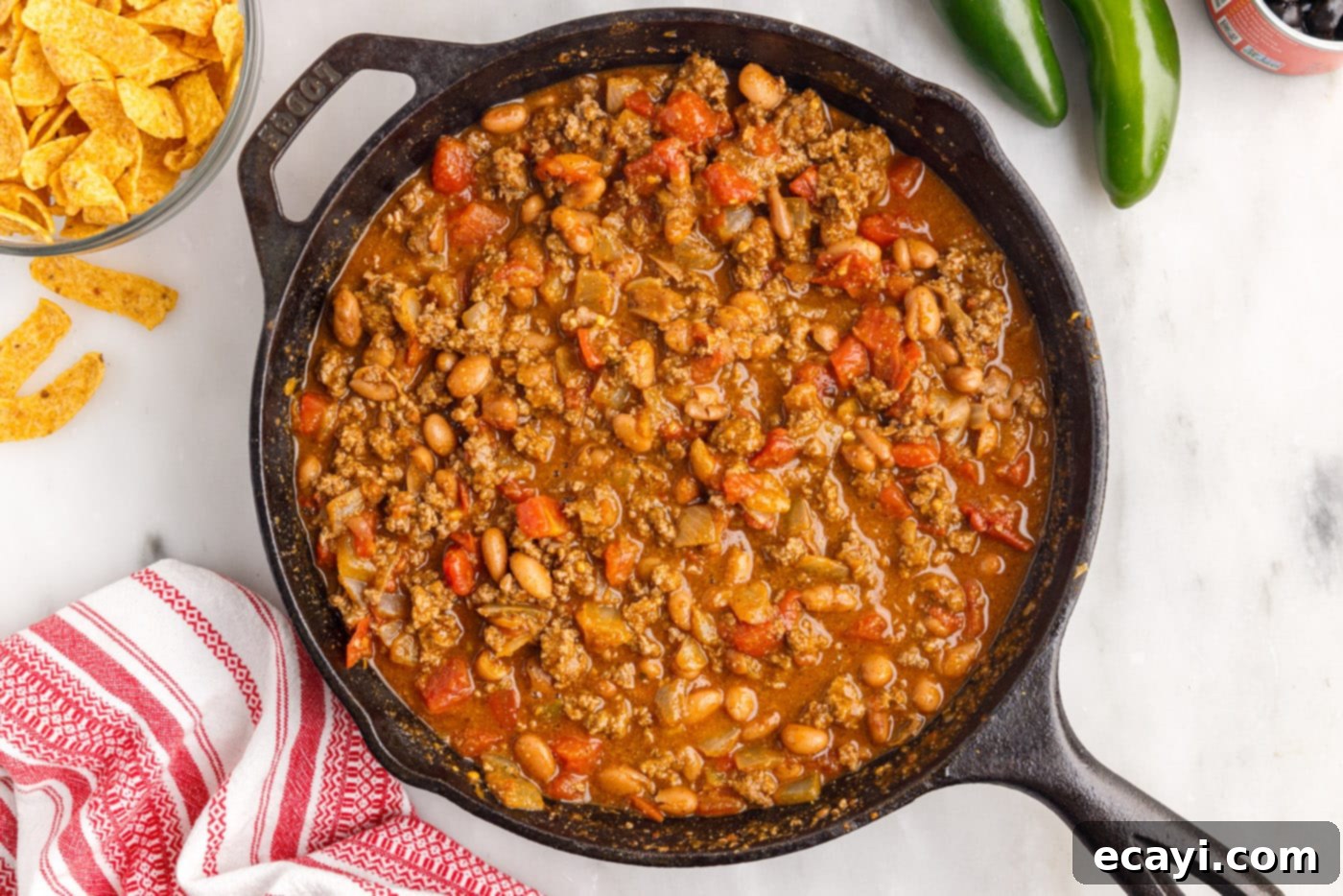 Crunchy Chili Cheese Delight 7 The ground beef mixture, now combined with seasonings, beans, and tomatoes, simmering gently in the skillet.