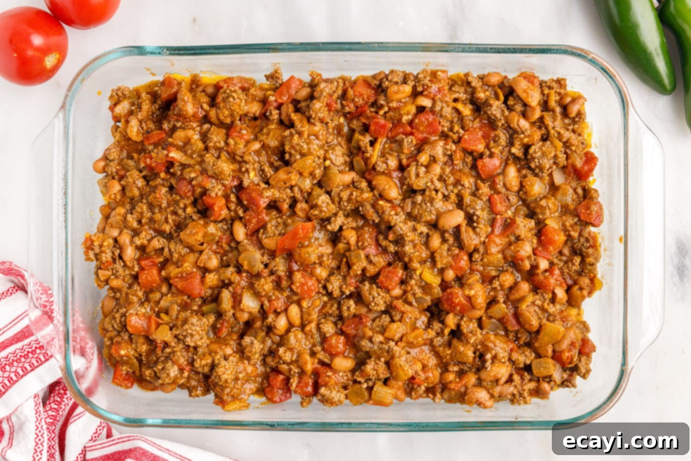 Crunchy Chili Cheese Delight 9 The seasoned meat mixture spread evenly over the initial layer of Fritos and cheese in the casserole dish.