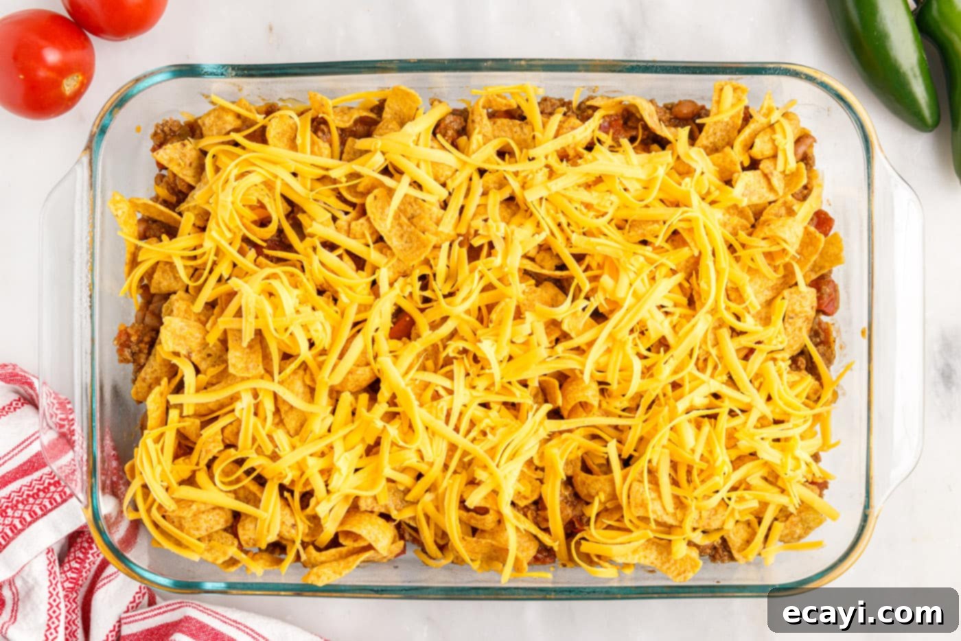 Crunchy Chili Cheese Delight 10 The final layer of Frito chips and shredded cheese placed on top of the meat mixture in the casserole dish, ready for baking.