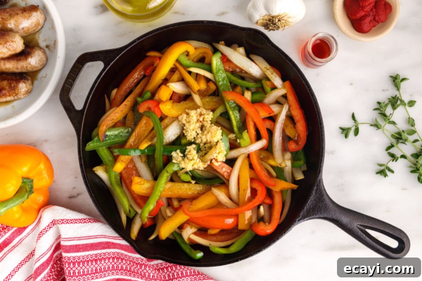 Sausage and Pepper Sizzle 8 Minced garlic added to the sautéed peppers and onions in a skillet, filling the air with aromatics.