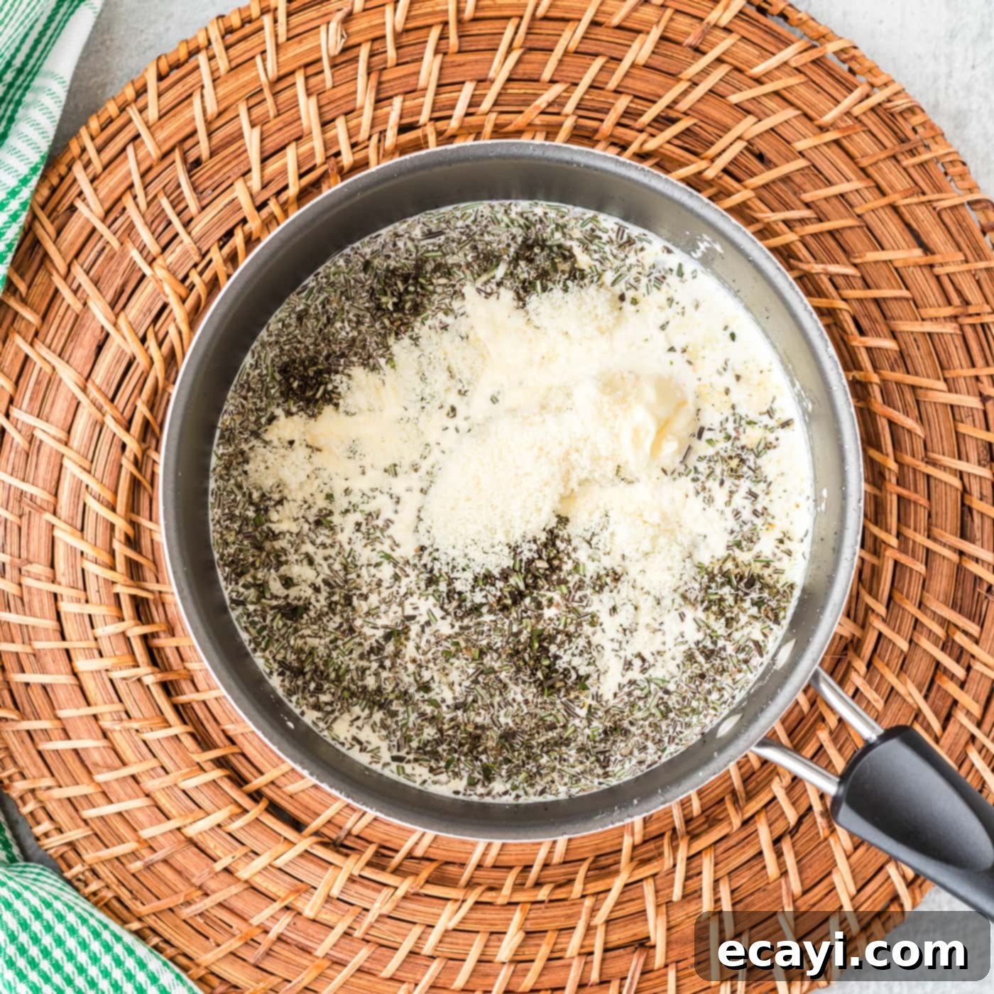 Aromatic Rosemary Cream Sauce 5 Rosemary cream sauce ingredients bubbling in a saucepan, being whisked to combine.