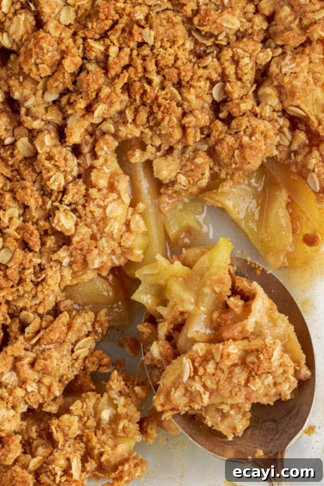 Warm Apple Crumble Delight 3 A spoon digging into a pan of golden brown apple crumble