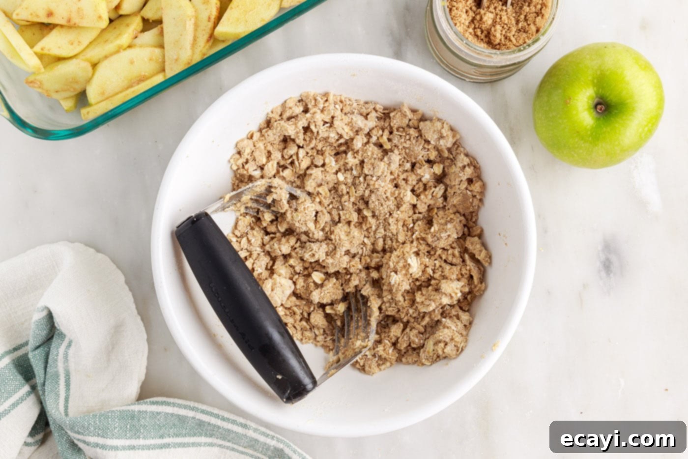Warm Apple Crumble Delight 9 A pastry cutter being used to blend butter into the dry oat mixture, creating a crumbly texture for the topping.