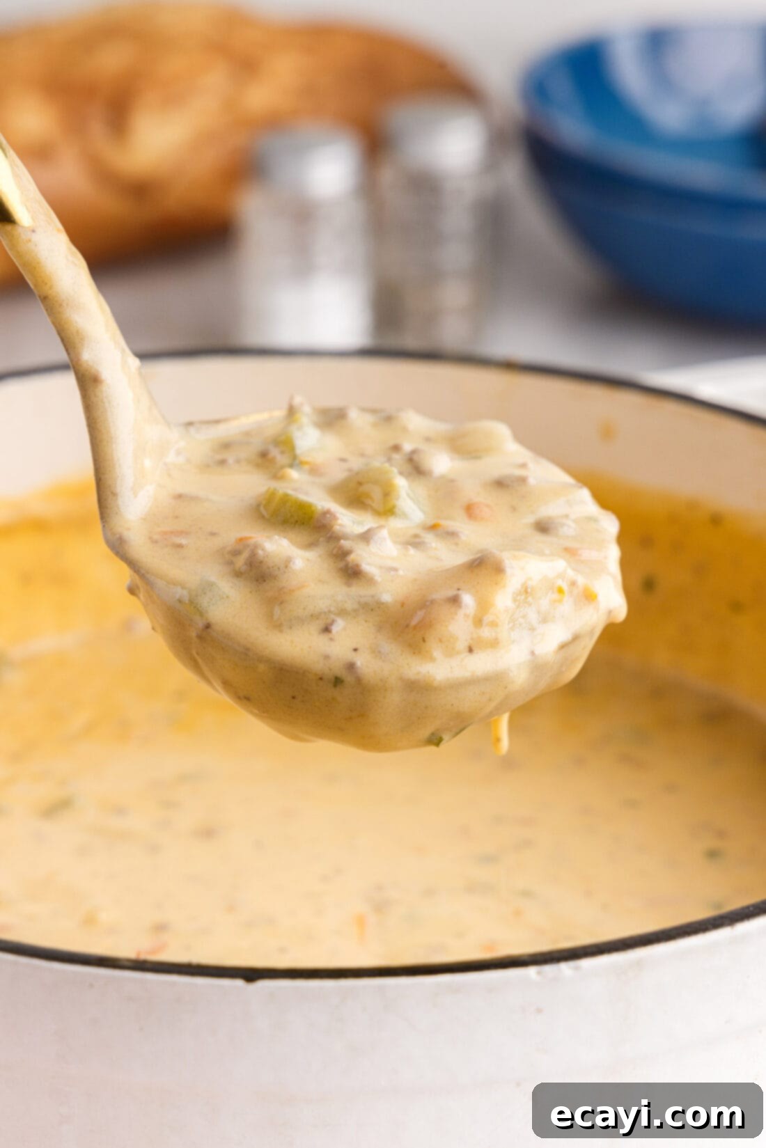 Hearty Cheeseburger Chowder 2 A ladle serving a generous portion of hearty cheeseburger soup into a bowl, showcasing the rich, creamy texture and visible pieces of ground beef, potatoes, and vegetables.
