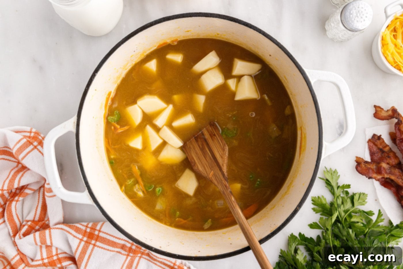Hearty Cheeseburger Chowder 11 Cubed potatoes added to the simmering broth and vegetables in a stockpot, ready to cook until tender.