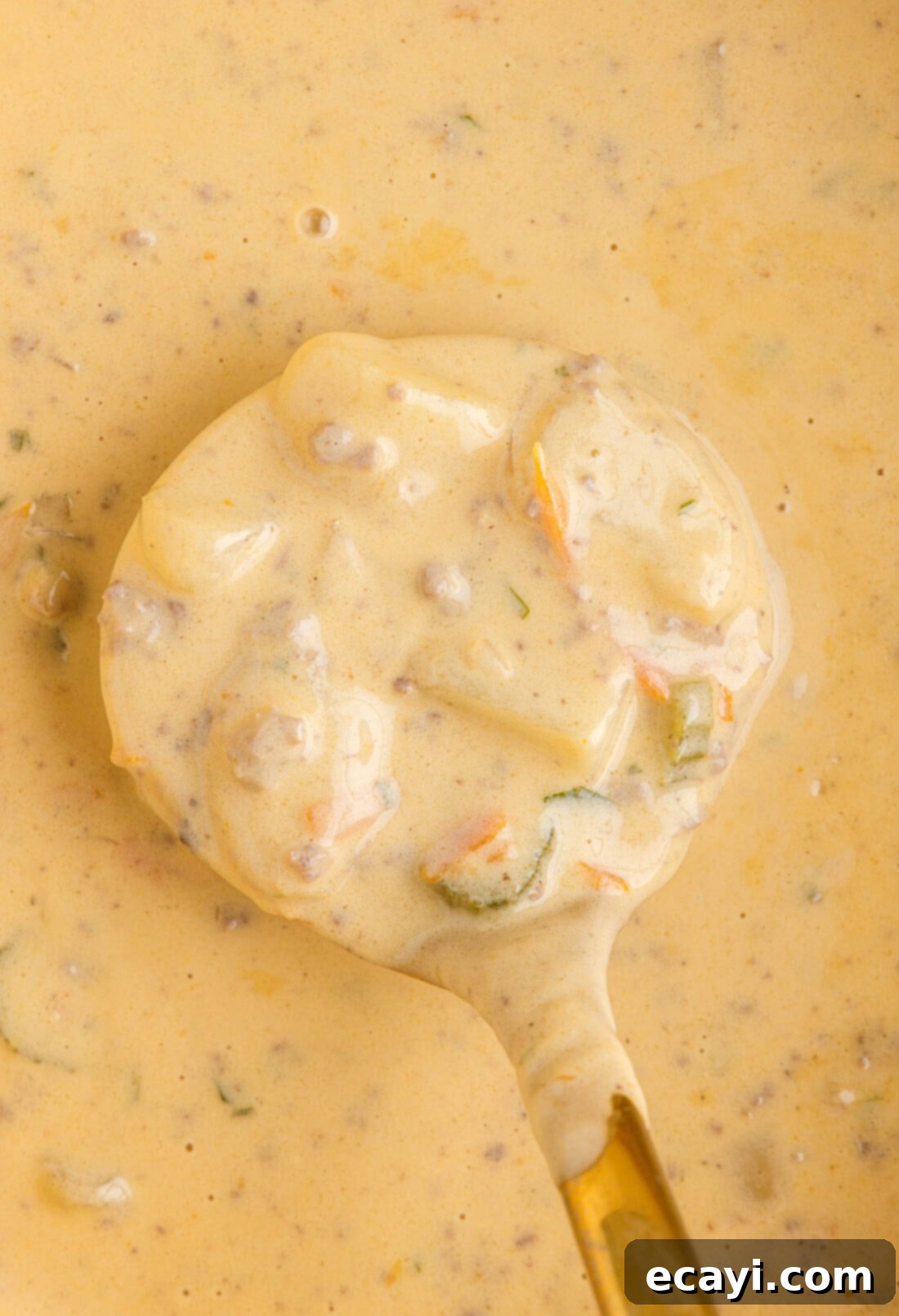 Hearty Cheeseburger Chowder 14 A delicious bowl of creamy cheeseburger soup with a spoon, garnished with fresh cheddar cheese and crumbled bacon, ready to be enjoyed.