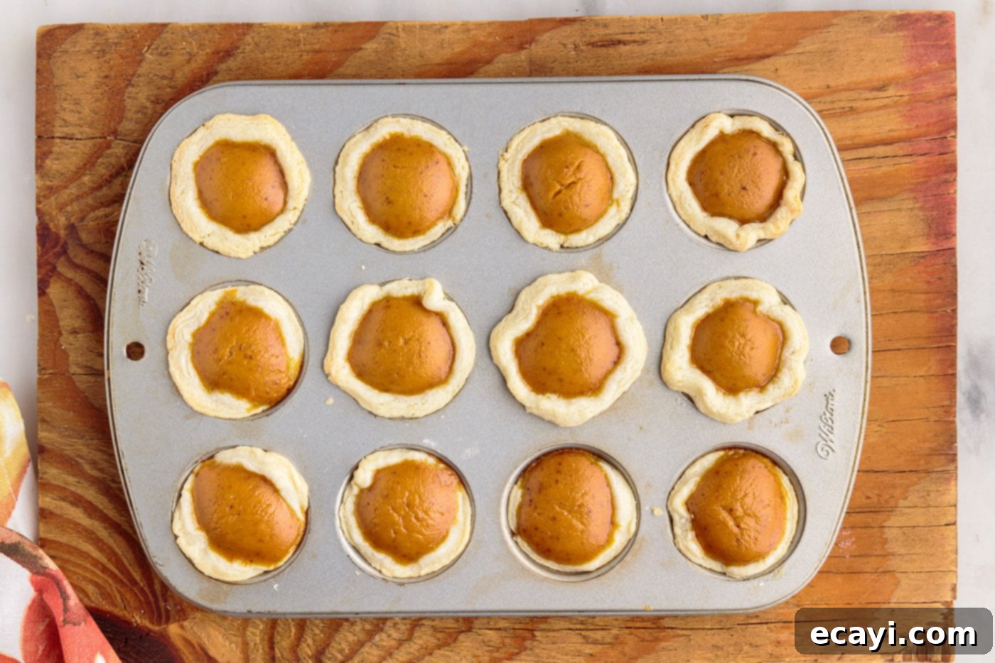 Pumpkin Pie Bites 15 mini pumpkin pies baked and cooling in a muffin tin