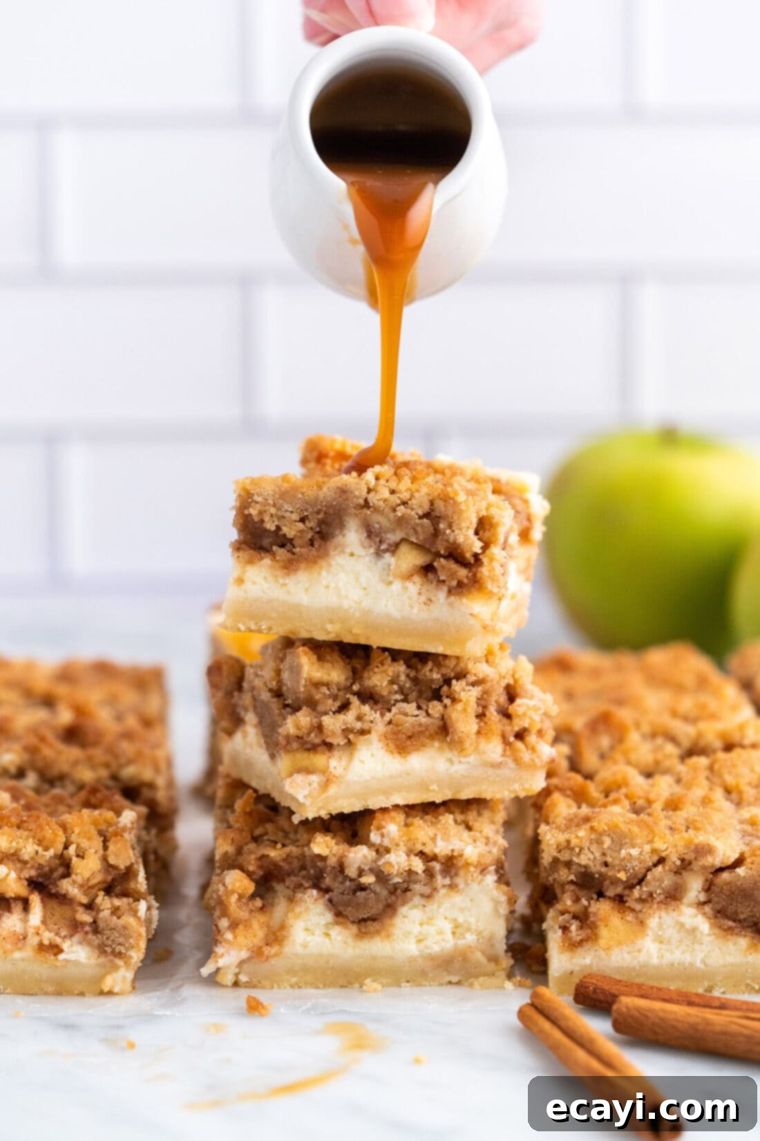 Harvest Caramel Apple Cheesecake Squares 19 Dripping caramel sauce onto a stack of Caramel Apple Cheesecake Bars