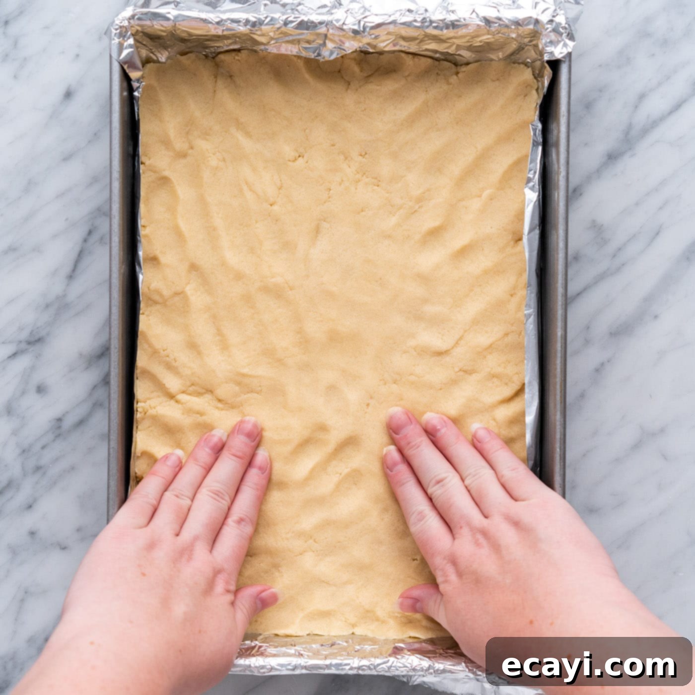 Harvest Caramel Apple Cheesecake Squares 10 Hands flattening shortbread crust in a baking pan to create an even layer
