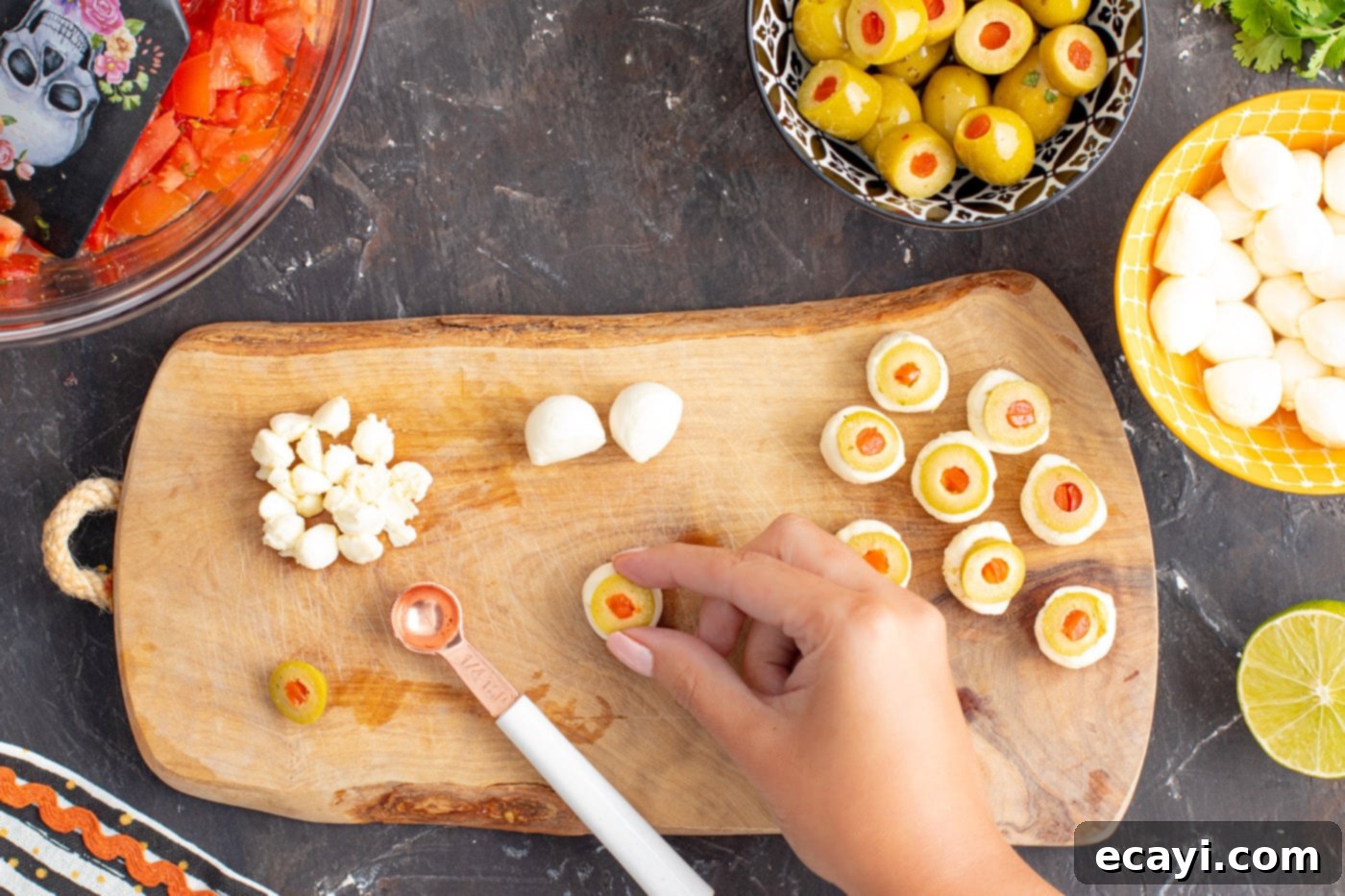 Eye-Popping Halloween Dip 10 placing a sliced pimento olive in the center of mozzarella balls