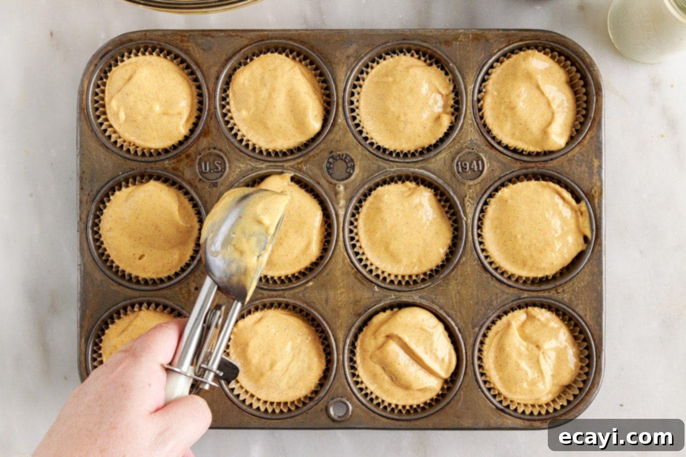 Spiced Mini Pumpkin Cheesecakes 11 adding pumpkin cheesecake filling to a muffin tin
