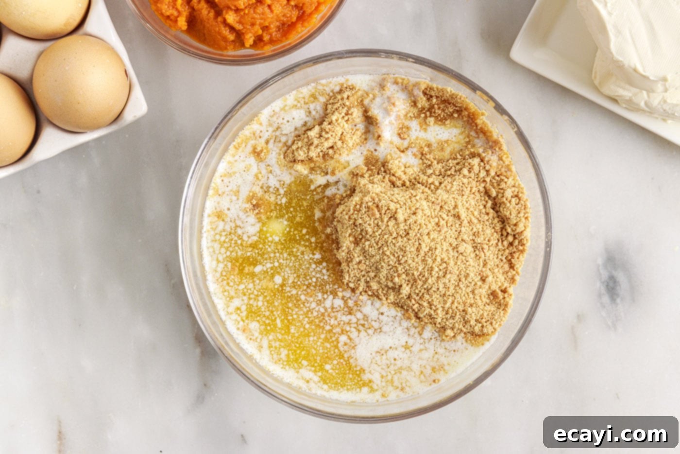 Spiced Mini Pumpkin Cheesecakes 5 graham cracker crumbs, butter, and sugar in a bowl