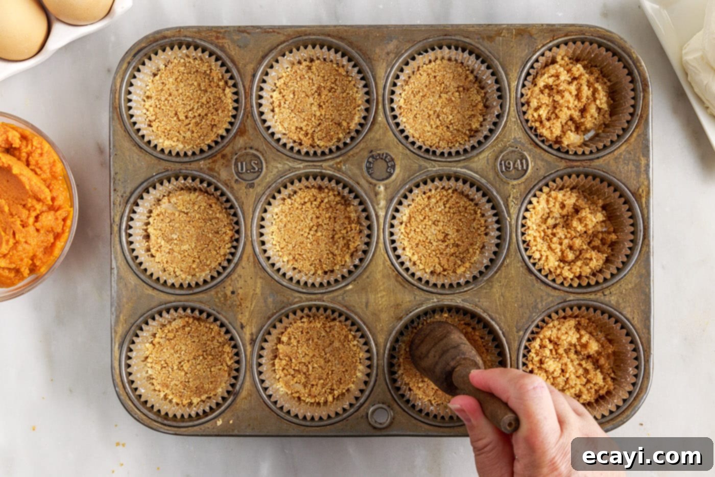 Spiced Mini Pumpkin Cheesecakes 7 pressing graham cracker crust into a muffin tin