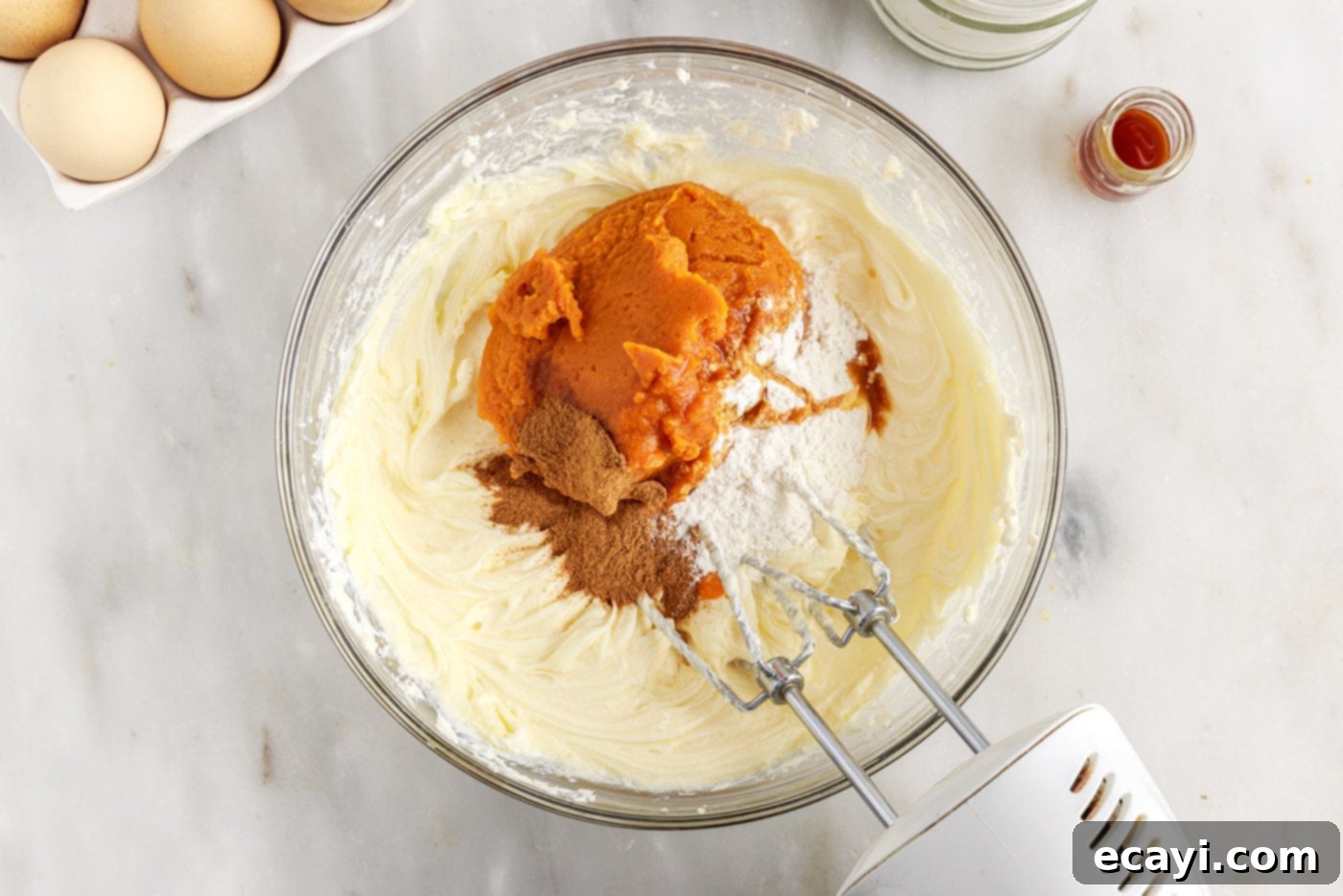Spiced Mini Pumpkin Cheesecakes 9 pumpkin cheesecake filling in a bowl with a mixer