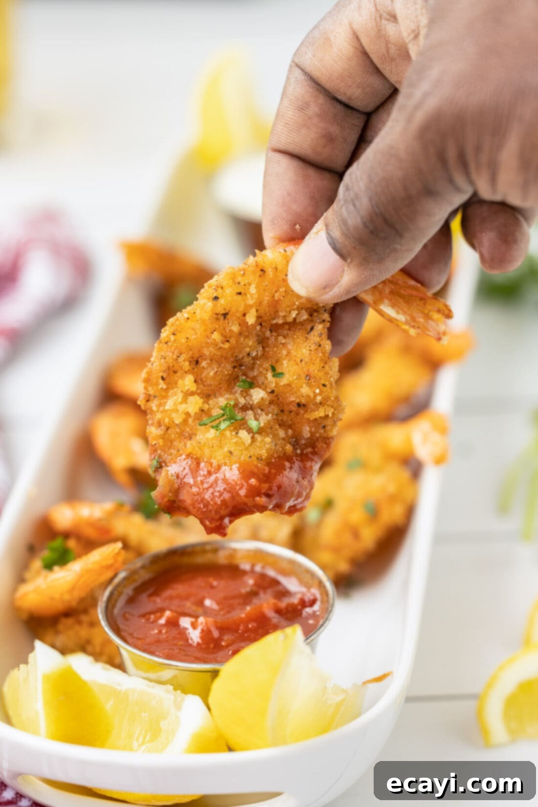 Golden Crispy Fanned Shrimp 3 dipping a Butterfly Shrimp in cocktail sauce