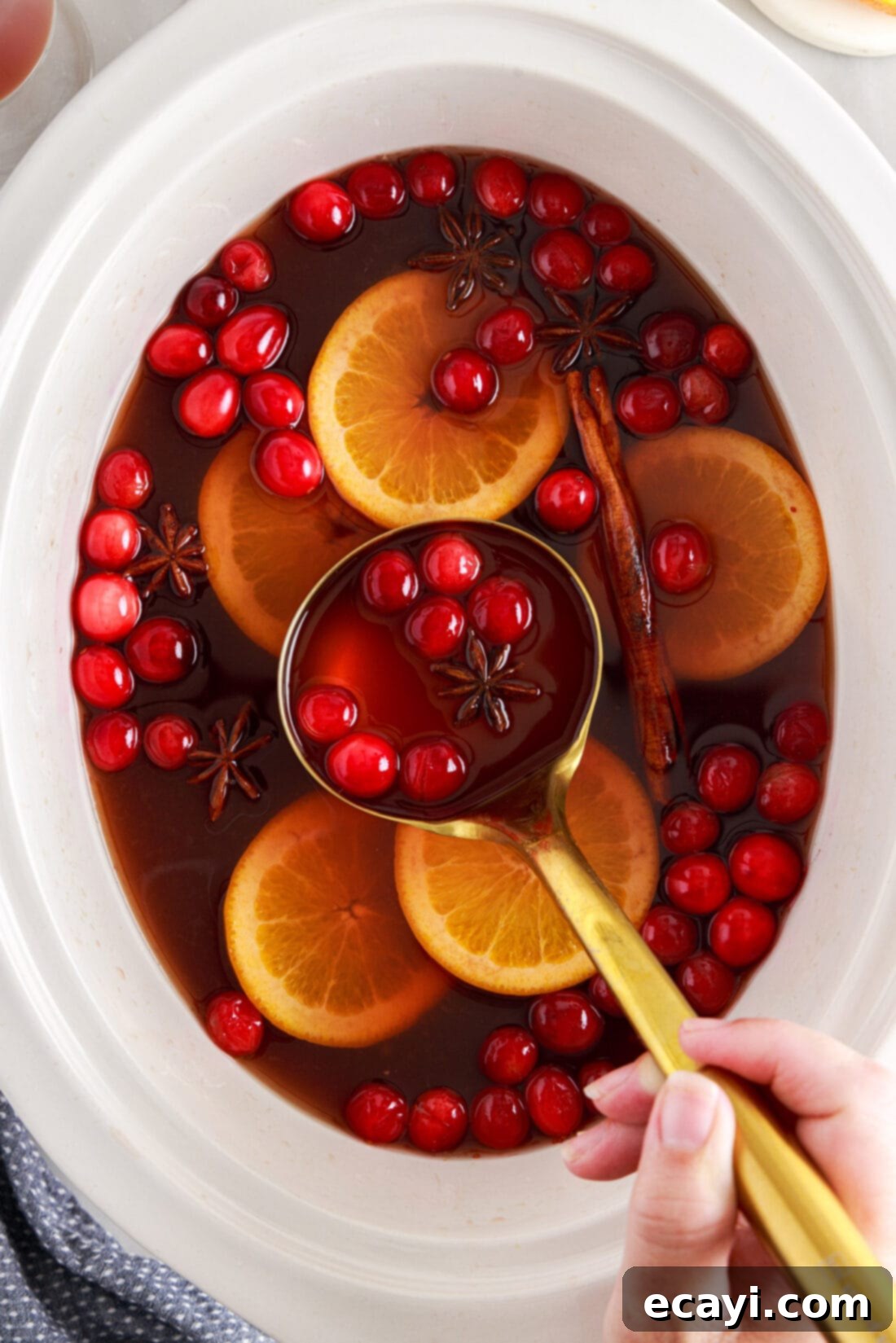 Mulled Cranberry Cheer 2 ladle of Hot Cranberry Punch being served, showing a rich red color and spices