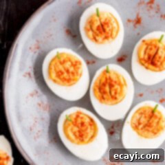 Creamy Pumpkin Deviled Delights 11 Pumpkin Deviled Eggs on a gray plate, garnished with paprika and chives