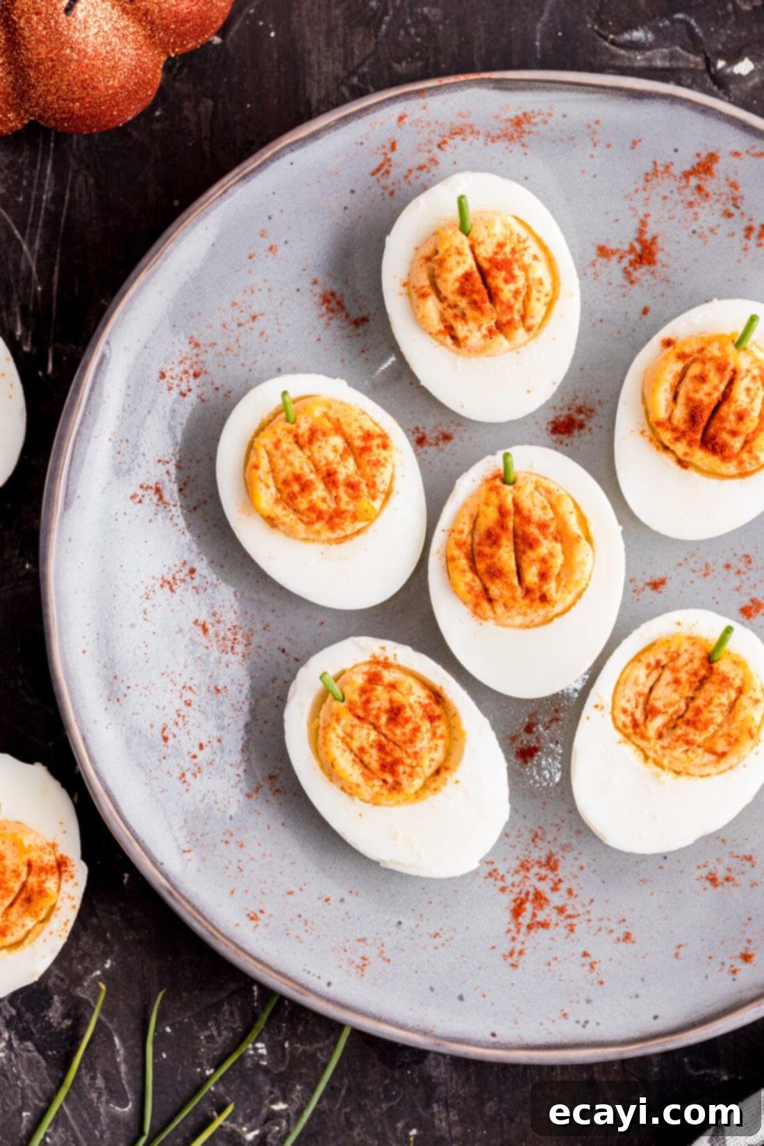 Creamy Pumpkin Deviled Delights 3 A vibrant plate filled with pumpkin-shaped deviled eggs, garnished with chives