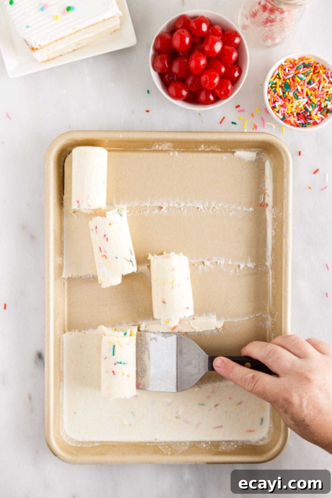 Confetti Cake Swirls 3 A spatula scraping and rolling Birthday Cake Rolled Ice Cream off a frozen pan.