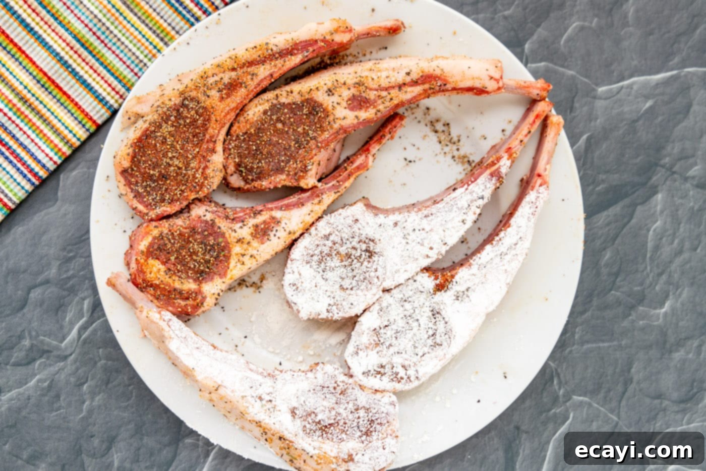 Gourmet Lamb Lollipops 6 A seasoned lamb chop being coated evenly with flour on a plate.