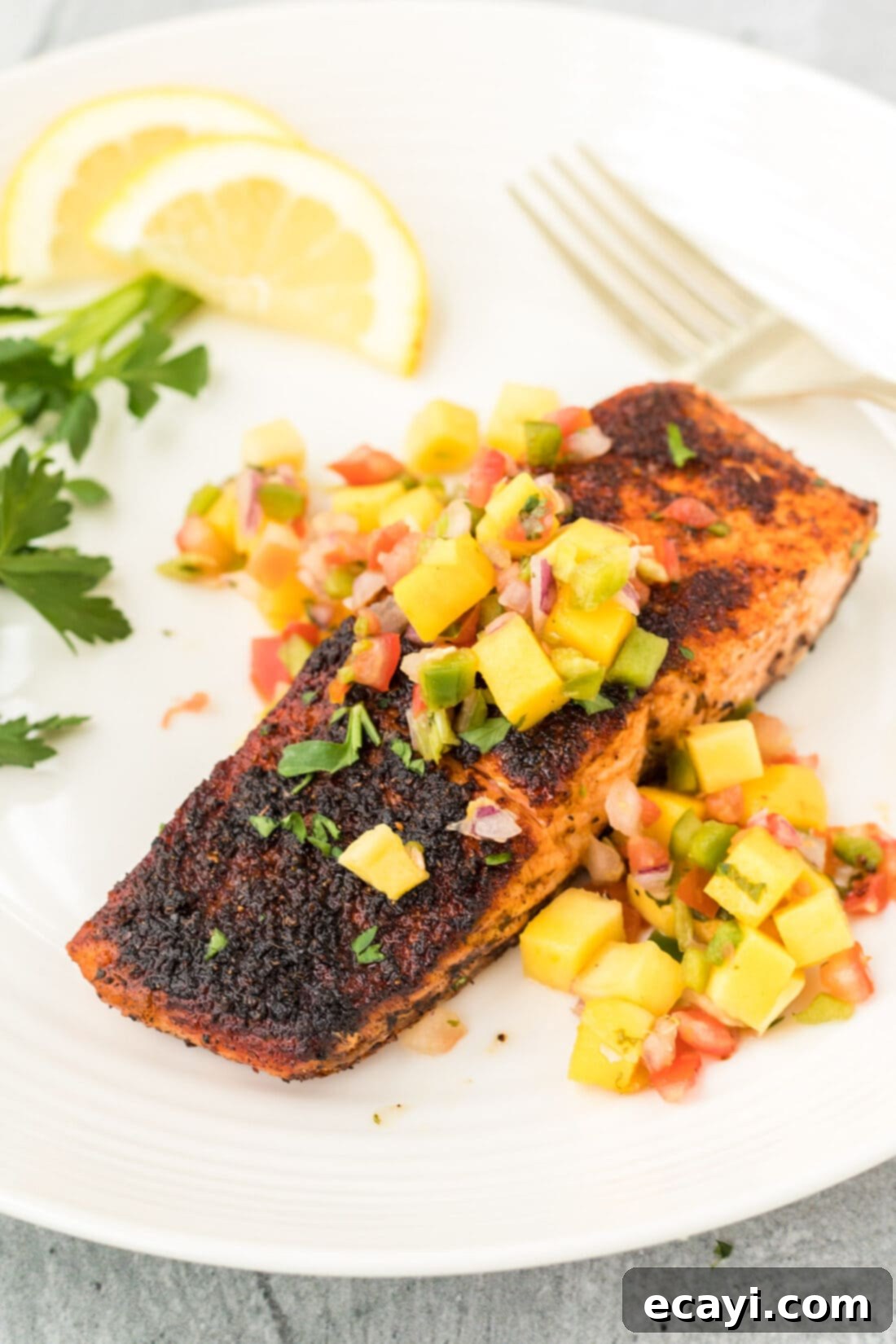 Cajun Seared Salmon 2 Blackened Salmon with mango salsa, served beautifully on a plate, highlighting the crispy crust and fresh side.
