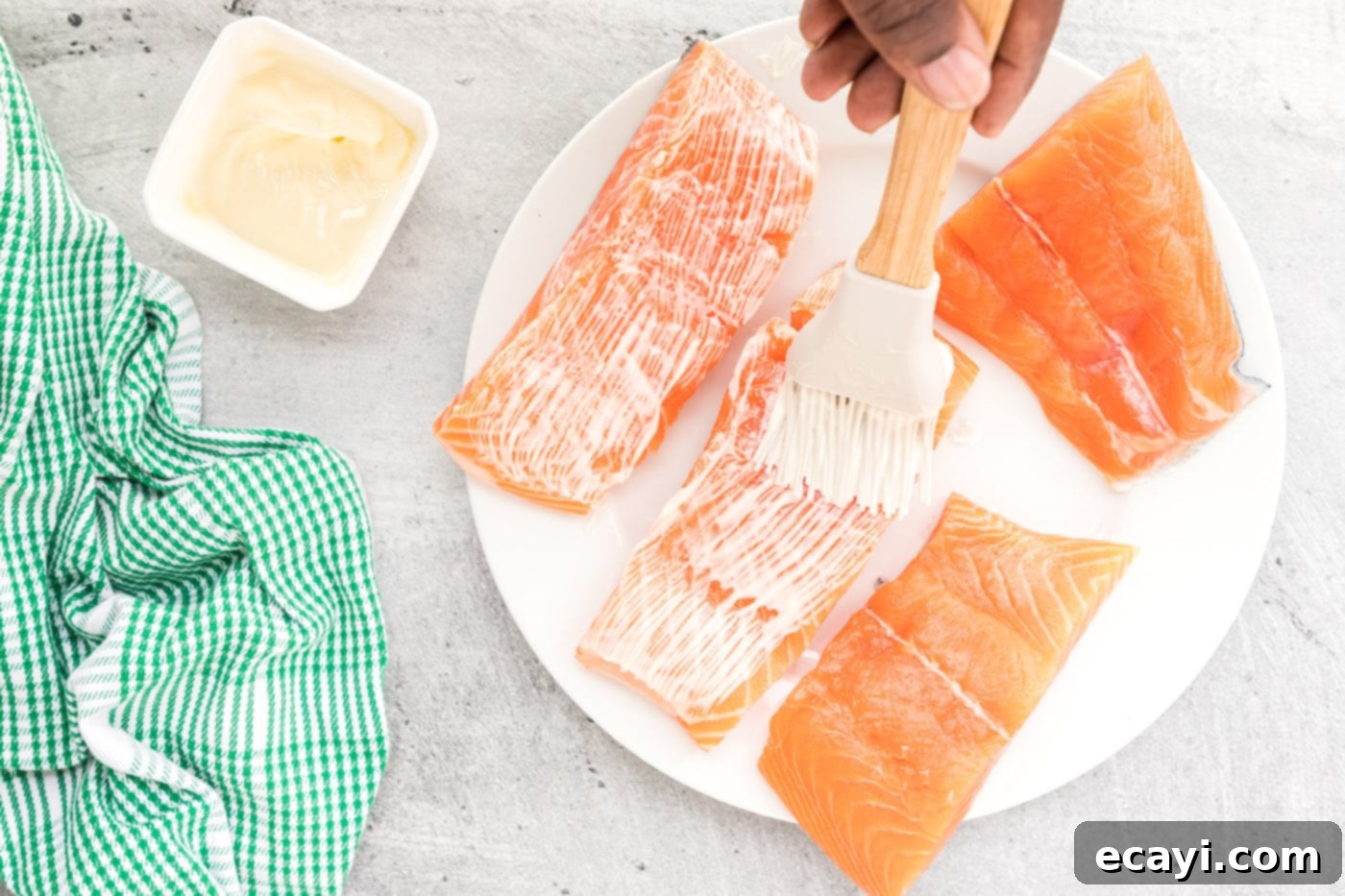 Cajun Seared Salmon 5 Fresh salmon fillets being brushed with softened butter, ensuring even coverage before seasoning.