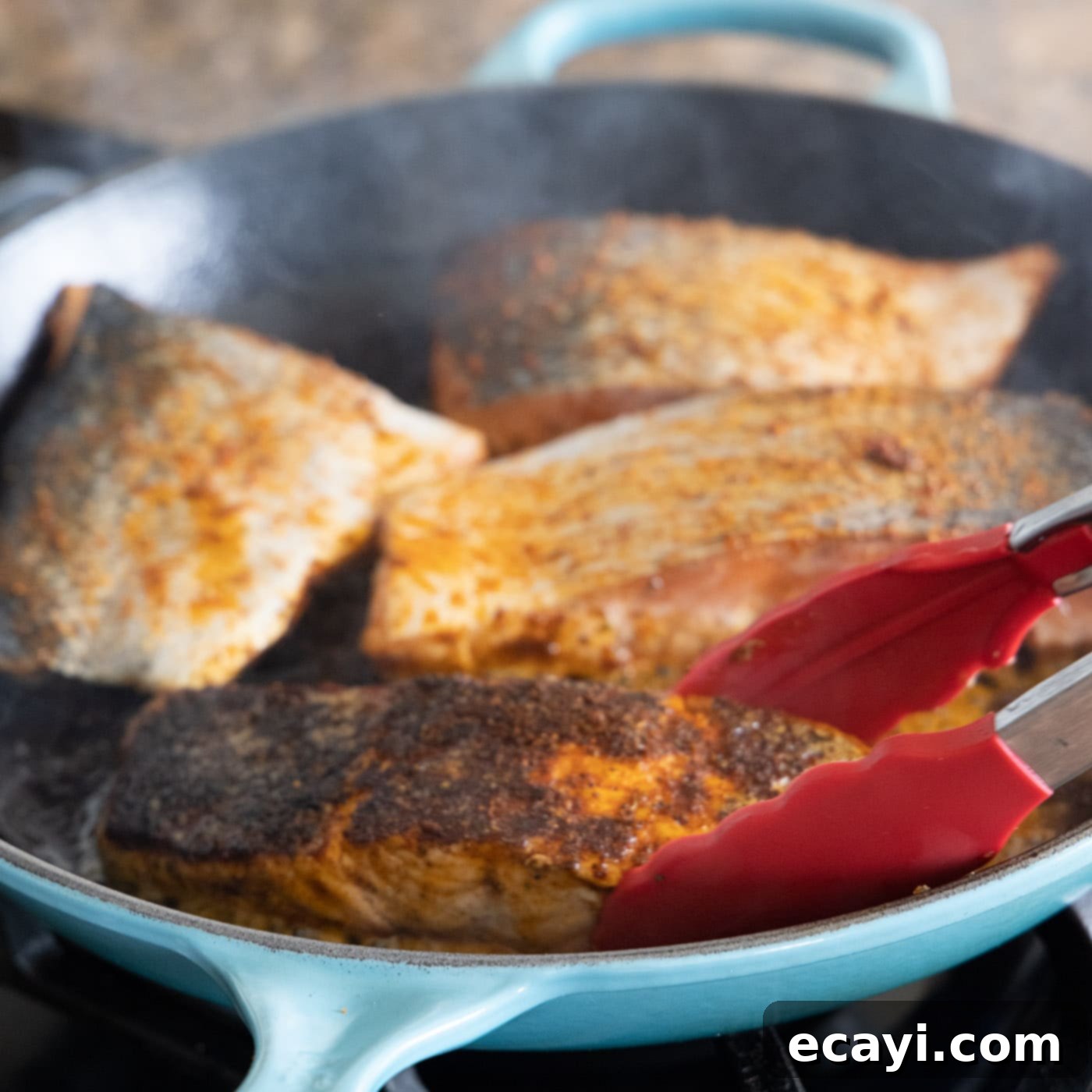 Cajun Seared Salmon 10 Blackened salmon fillets, cooked to a perfect dark crust, resting in a skillet after being flipped.