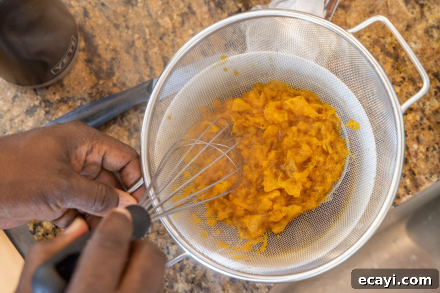Zesty Peppercorn Shrimp 14 A fine mesh strainer being used to separate the clementines from the cooked sauce.