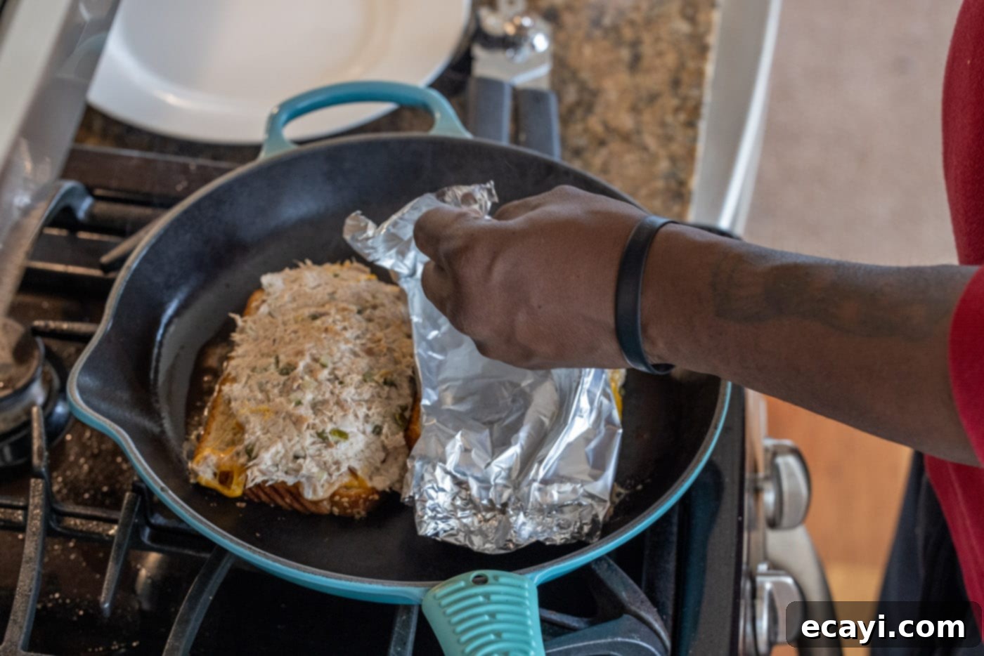 Golden Tuna Grille 12 Gently lifting the foil away from the tuna melt, revealing the perfectly assembled sandwich.
