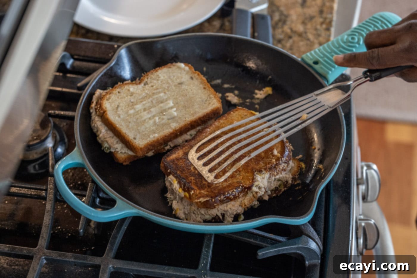 Golden Tuna Grille 14 Carefully flipping a tuna melt in a skillet to toast the second side.