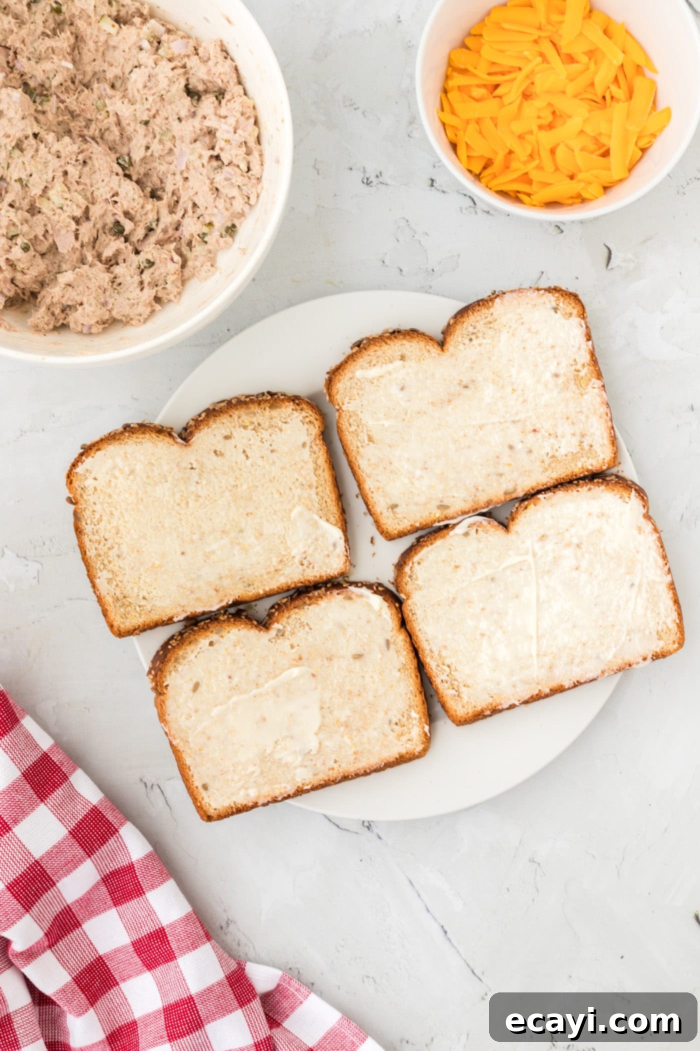 Golden Tuna Grille 5 Buttered multigrain bread slices ready for assembly on a plate.