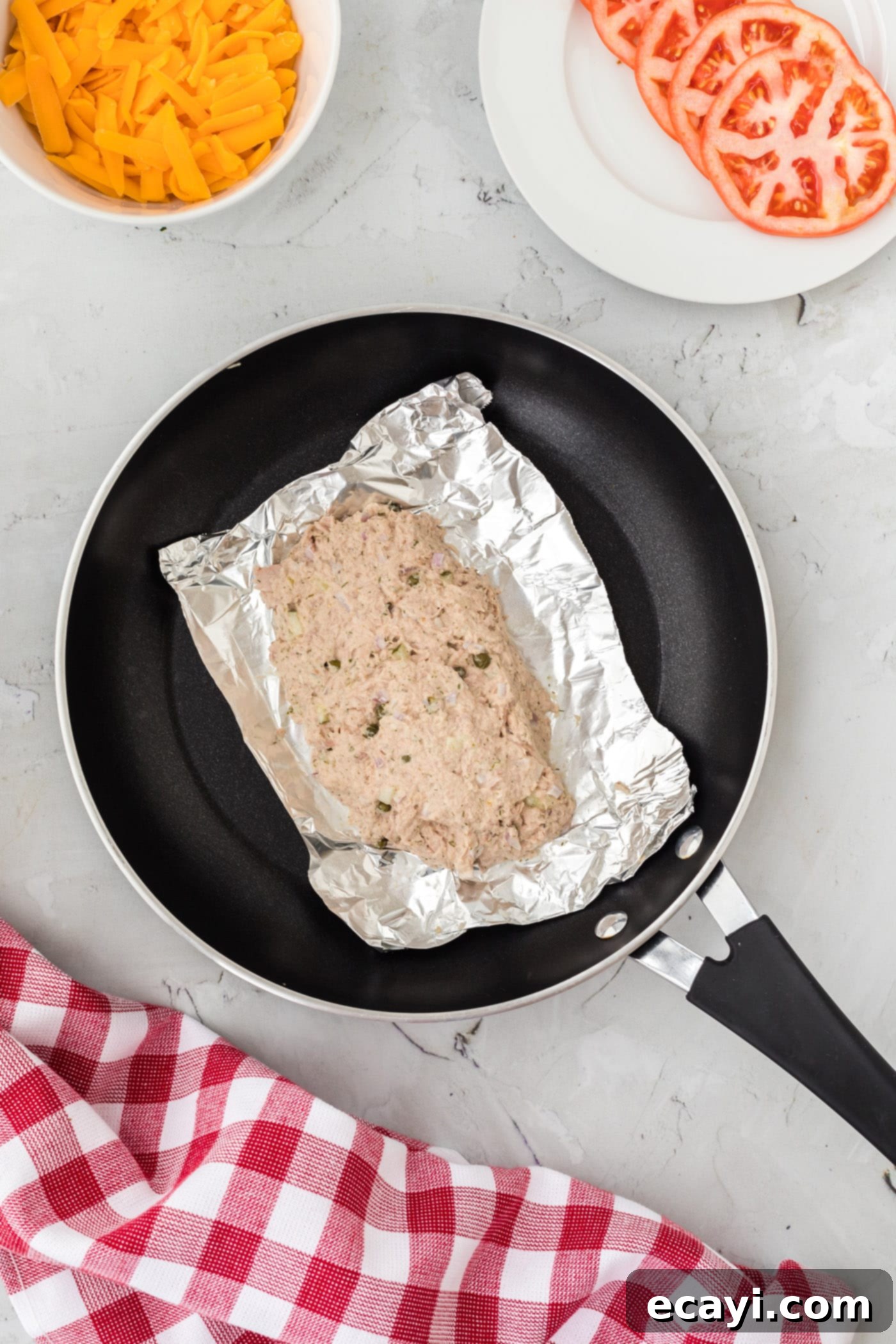 Golden Tuna Grille 6 Tuna salad neatly placed in an aluminum foil bowl inside a hot skillet, ready for cheese and steaming.
