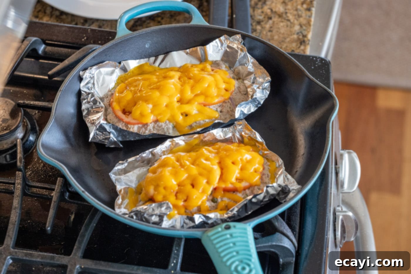 Golden Tuna Grille 10 Melted cheese cascading over the tuna melt ingredients in a foil bowl, removed from the skillet.