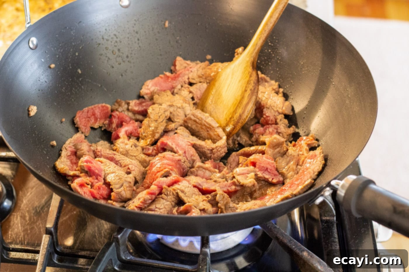 Ultimate Beef Lo Mein 6 wooden spoon stirring sliced steak in a wok