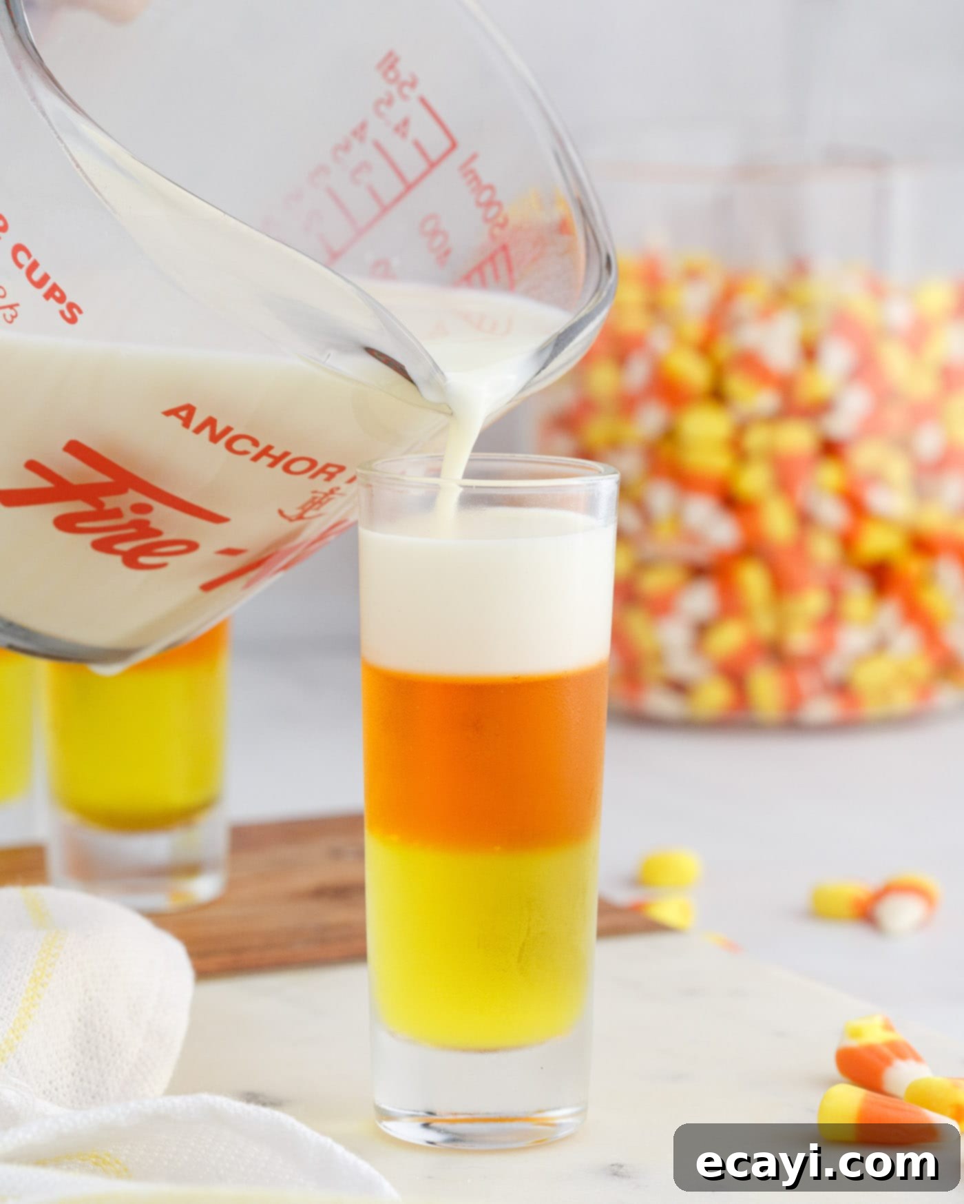 Harvest Hues Shooters 10 pouring condensed milk gelatin on top of candy corn jello shots