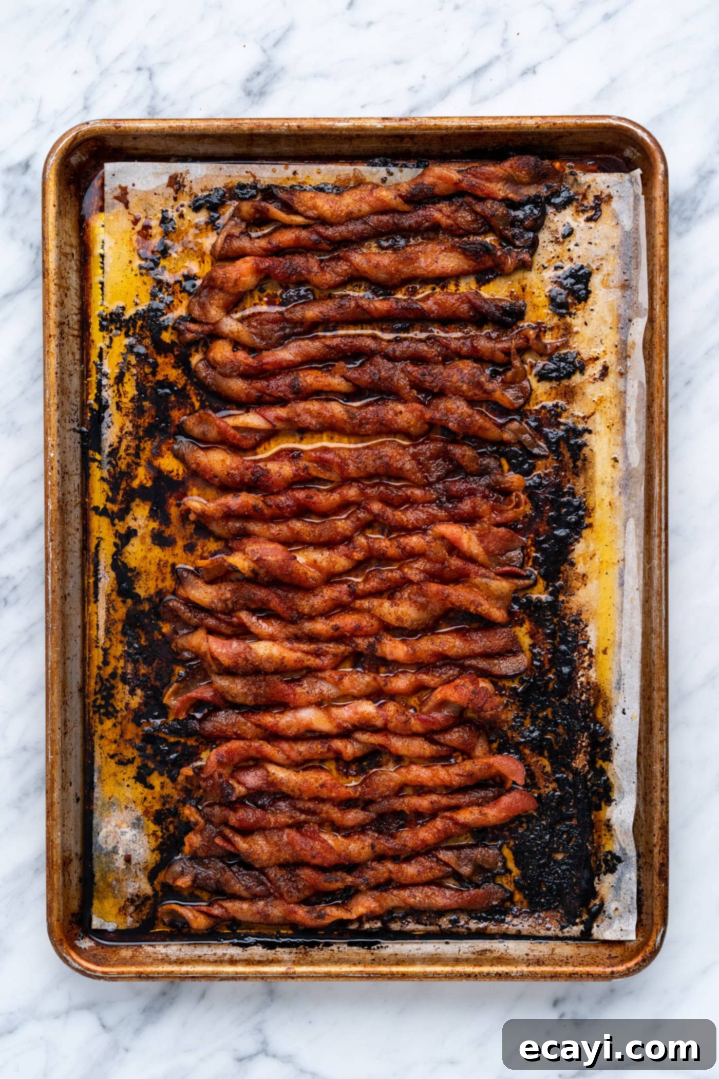 Crispy Bacon Spirals 9 Oven-baked bacon twists turning golden brown on a baking sheet