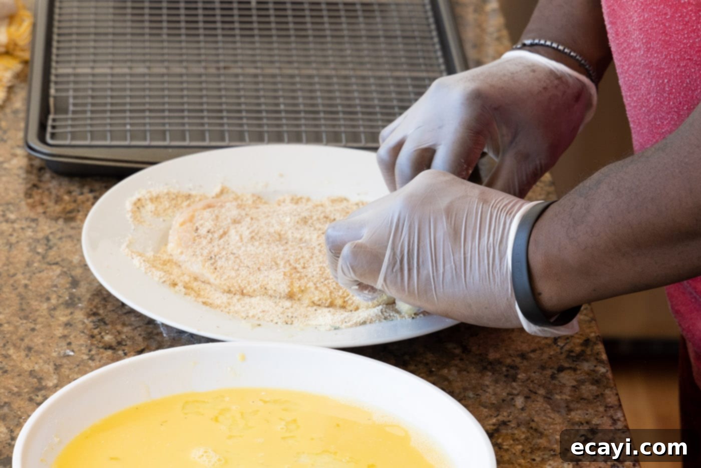 Crispy Chicken Milanese 11 Laying a chicken cutlet into breadcrumb mixture, ensuring even coating