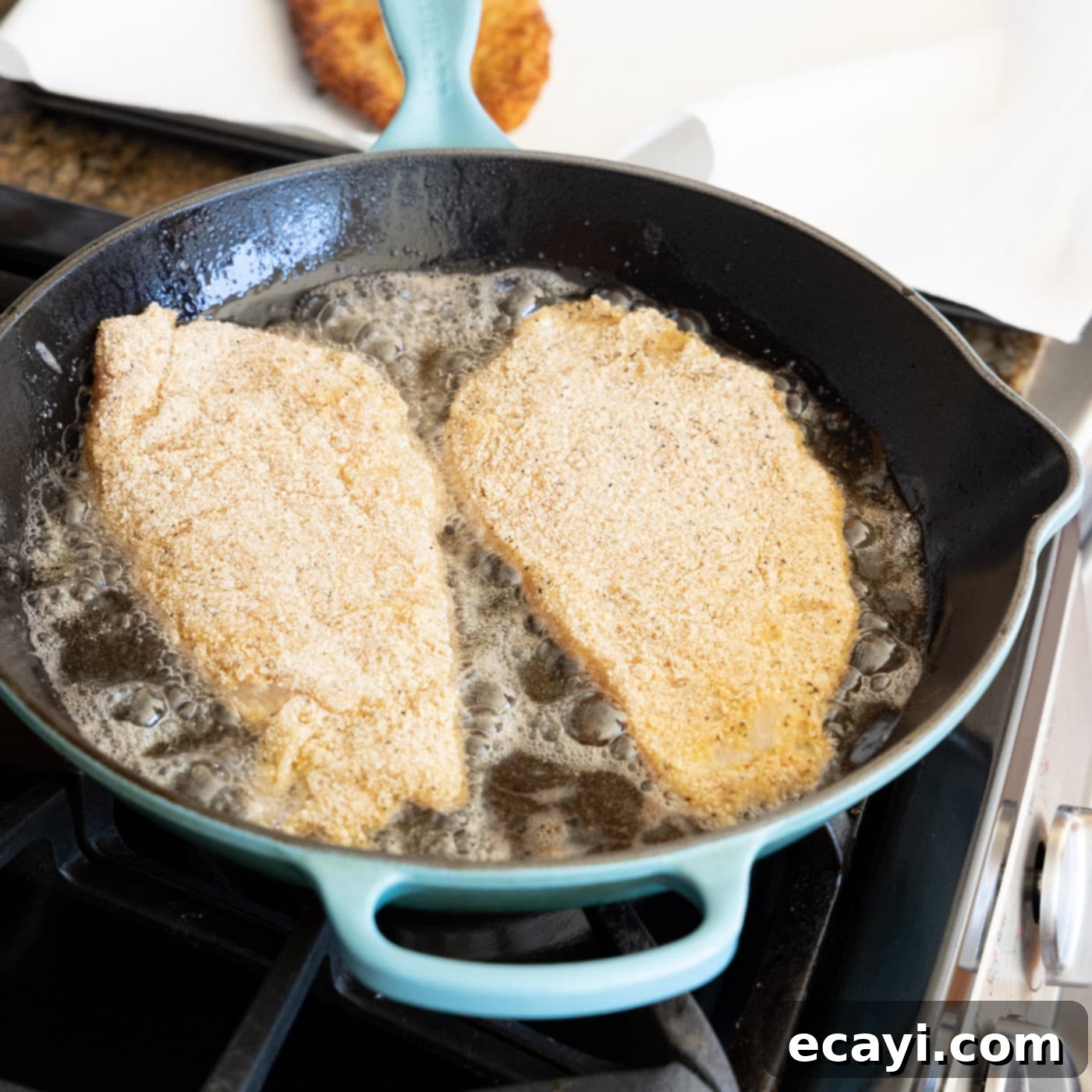 Crispy Chicken Milanese 12 Chicken cutlets frying in a skillet with shimmering olive oil