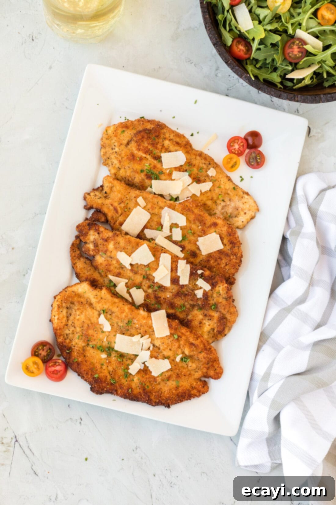 Crispy Chicken Milanese 3 Platter of golden brown Chicken Milanese garnished with fresh herbs