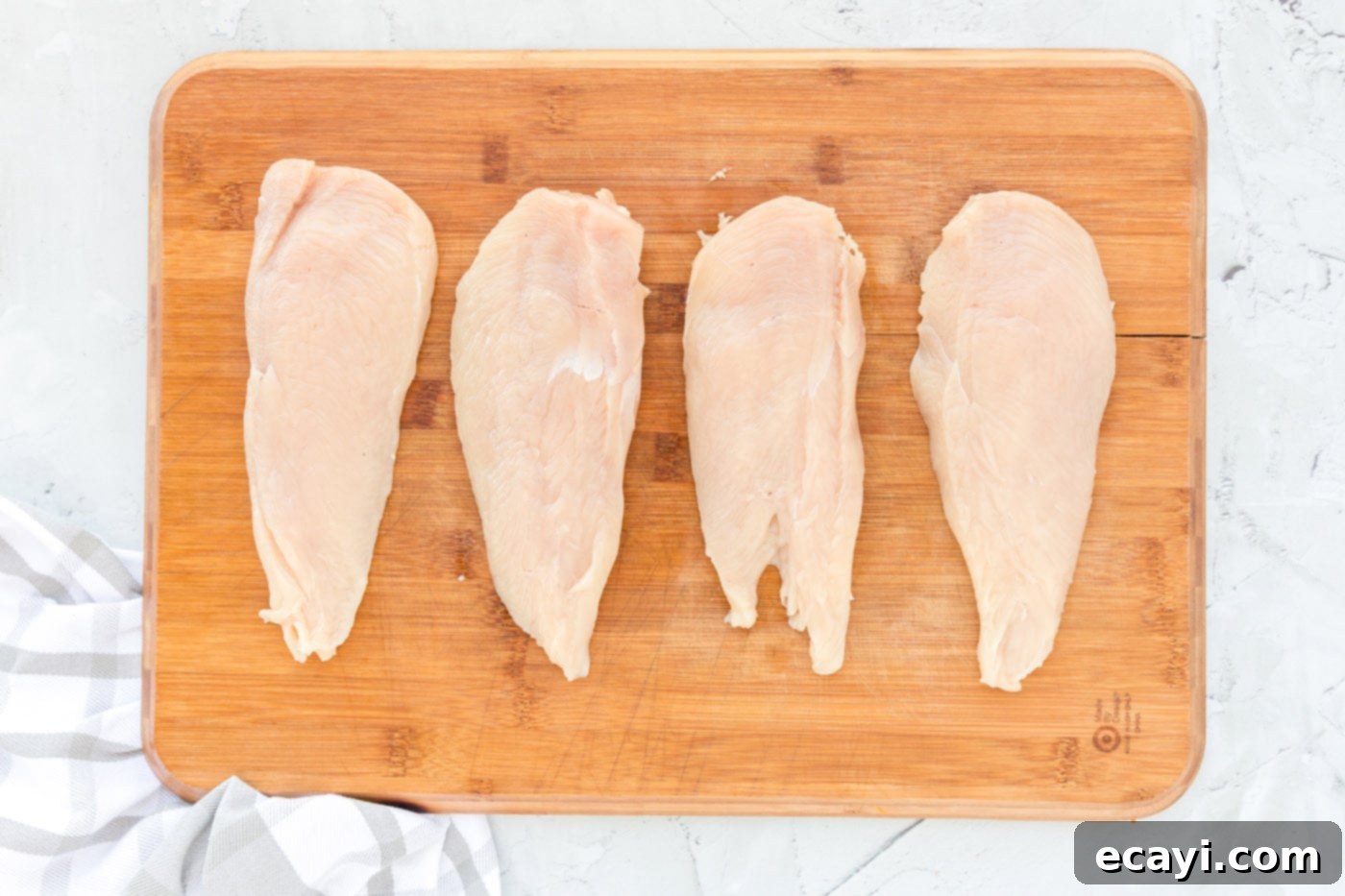 Crispy Chicken Milanese 5 Chicken cutlets on a cutting board, prepared for pounding