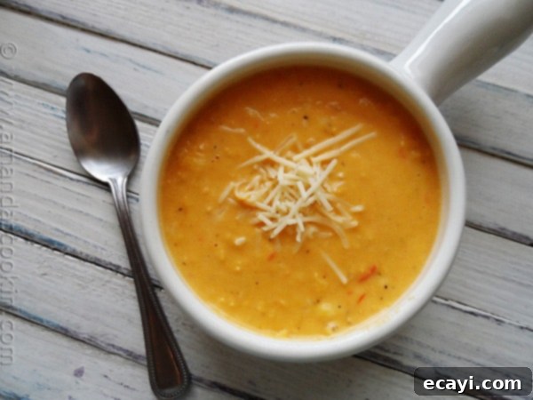 Creamy White Cheddar Corn Soup - AmandasCookin.com A close up photo of a bowl of creamy white cheddar corn soup with visible red bell pepper bits.
