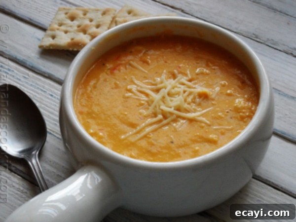 Creamy White Cheddar Corn Soup - AmandasCookin.com A close up photo of a bowl of creamy white cheddar corn soup with a spoon.