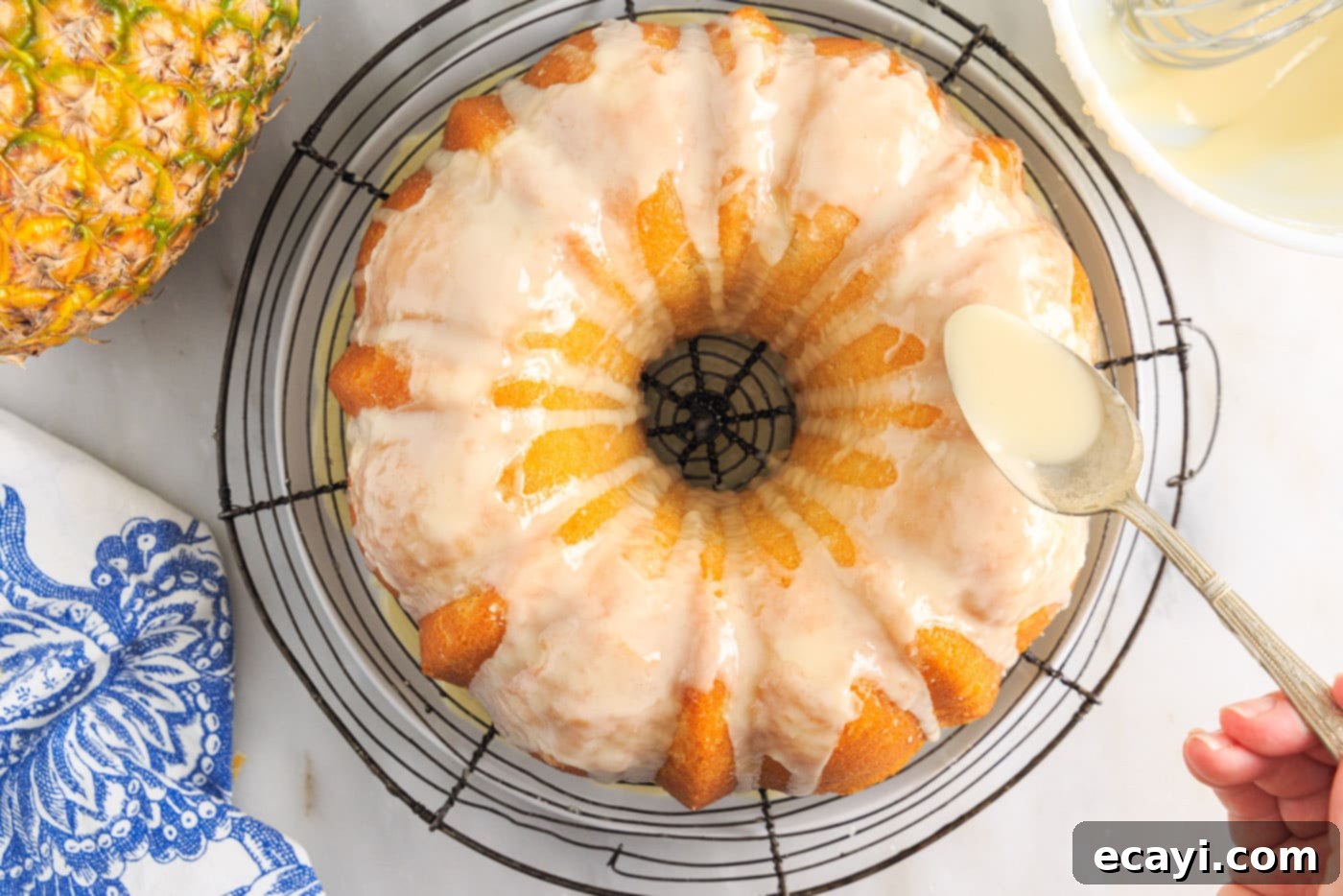 Sunshine Pineapple Pound Cake 13 A finished Pineapple Pound Cake being drizzled with a sweet vanilla pineapple glaze, showcasing its glossy finish.
