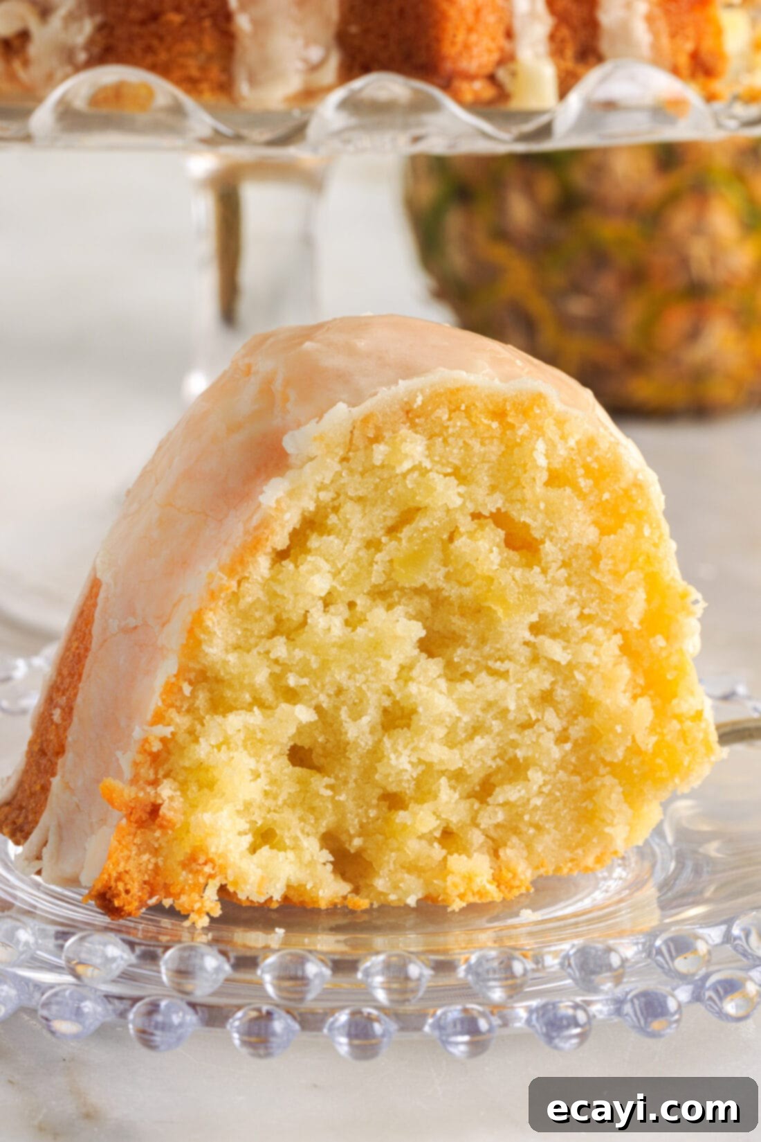 Sunshine Pineapple Pound Cake 14 A delicious slice of Pineapple Pound Cake with glaze, served on a white plate, highlighting its tender and moist texture.