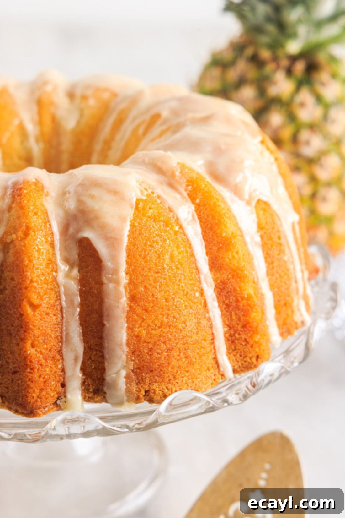 Sunshine Pineapple Pound Cake 3 A whole Pineapple Pound Cake elegantly presented on a cake plate, ready to be served, showcasing the beautiful glaze.