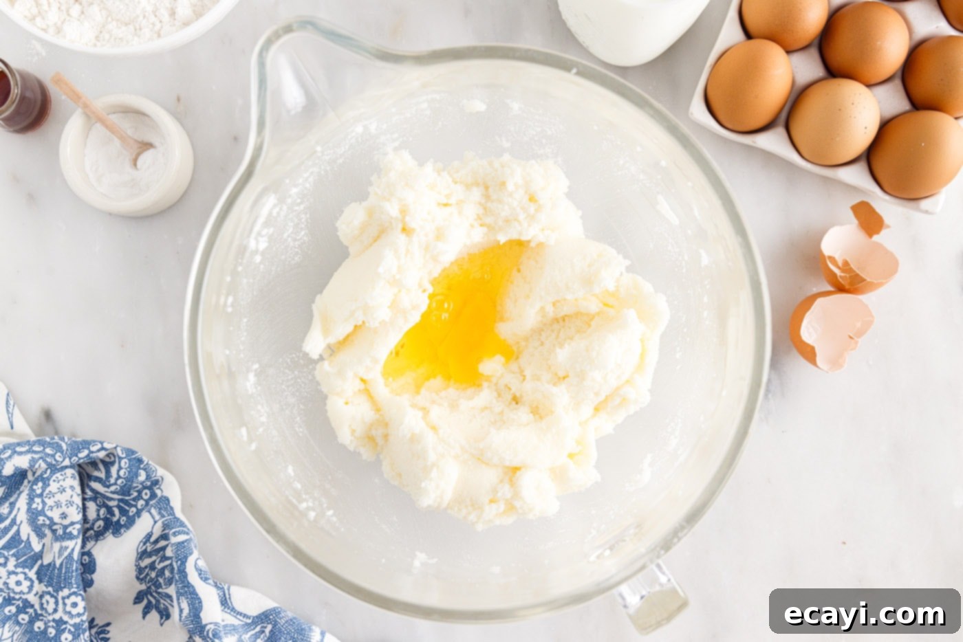 Sunshine Pineapple Pound Cake 6 Room temperature eggs being added one by one to the creamed butter, shortening, and sugar mixture in a mixing bowl.