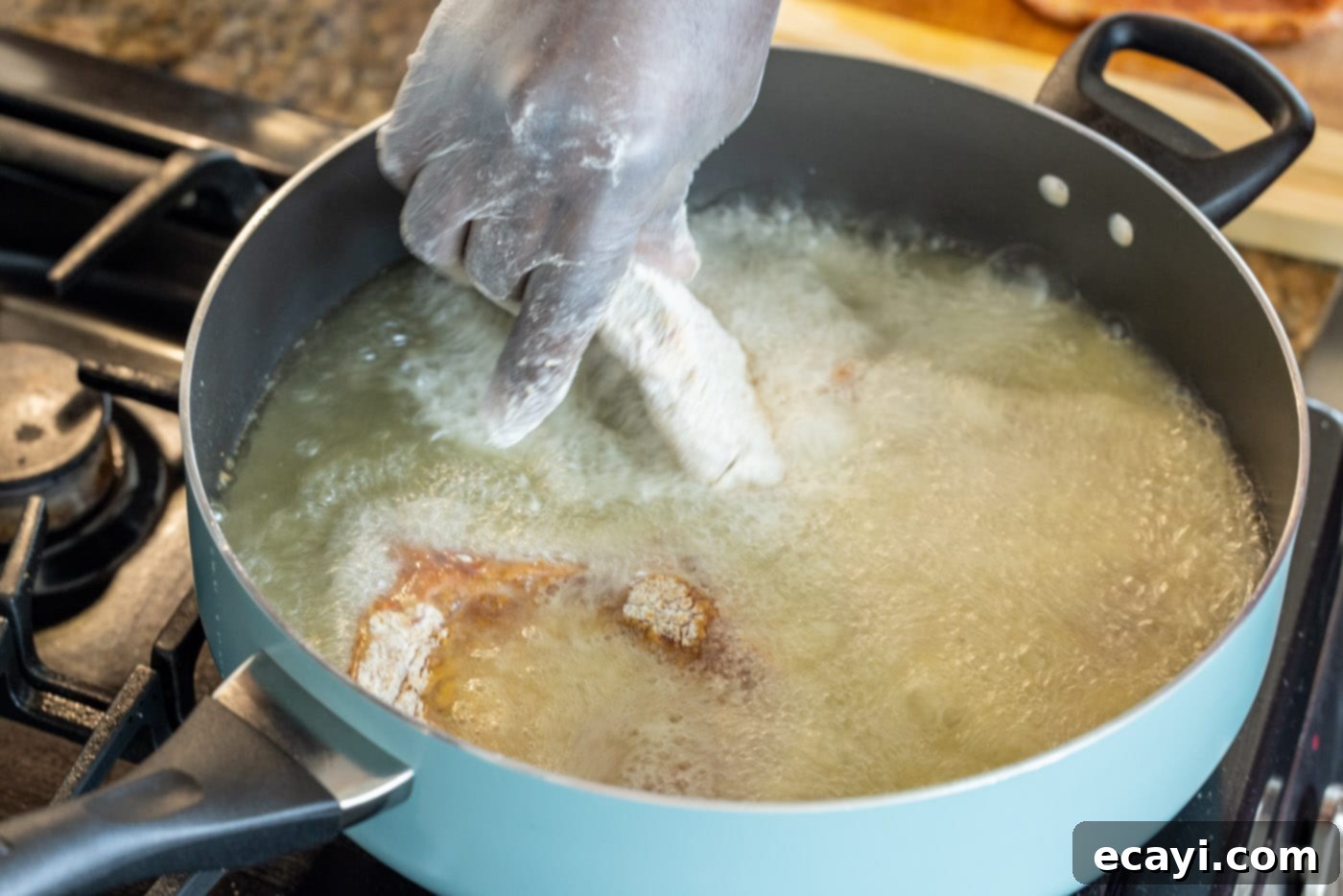 Golden Crispy Pork Chops 8 Placing a floured pork chop into a hot skillet with vegetable oil using tongs