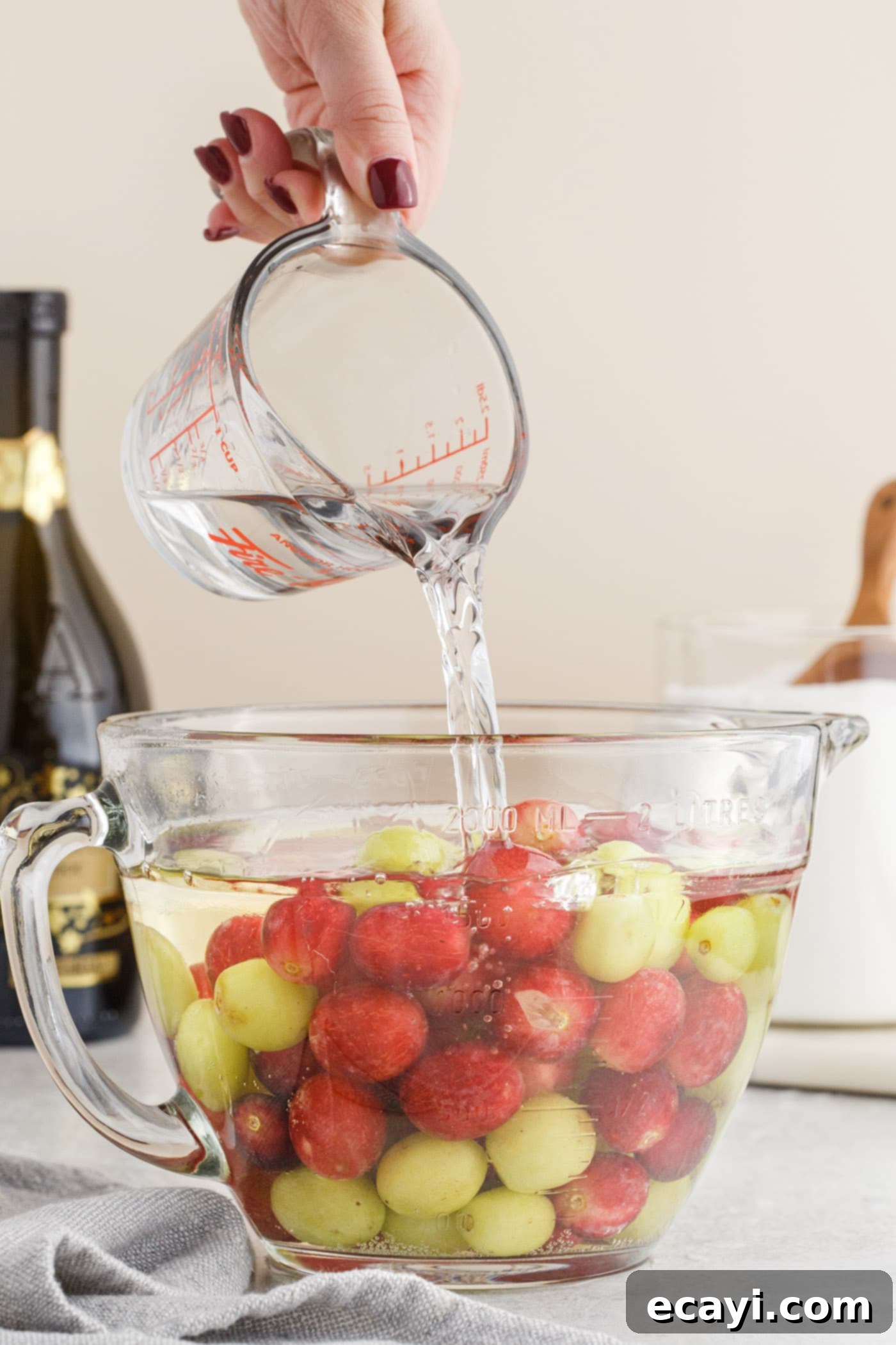 Prosecco Vodka Grape Fusion 6 pouring vodka over prosecco and grapes in a bowl