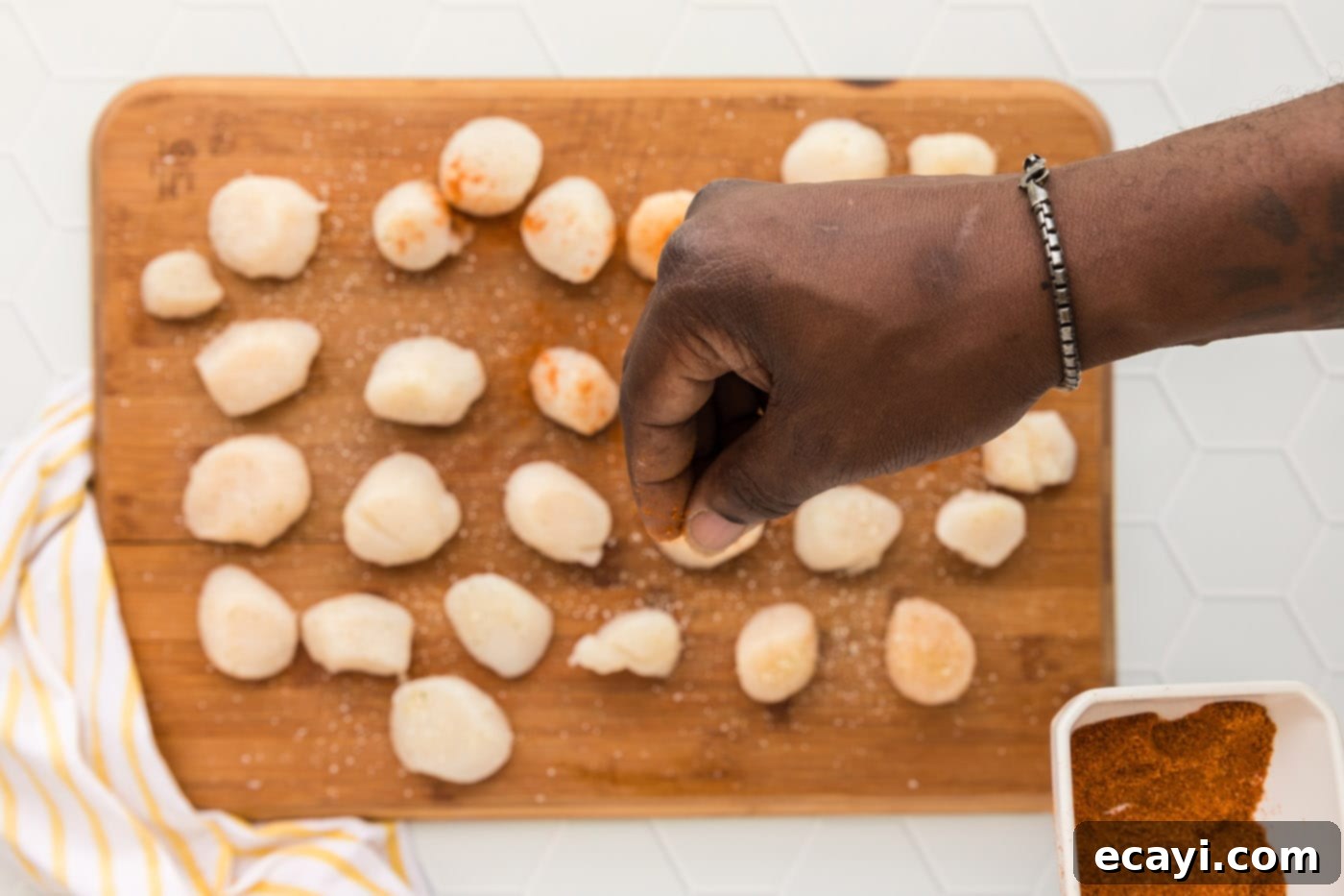 Perfect Air Fryer Scallops 5 seasoning scallops on a cutting board with garlic salt and Old Bay